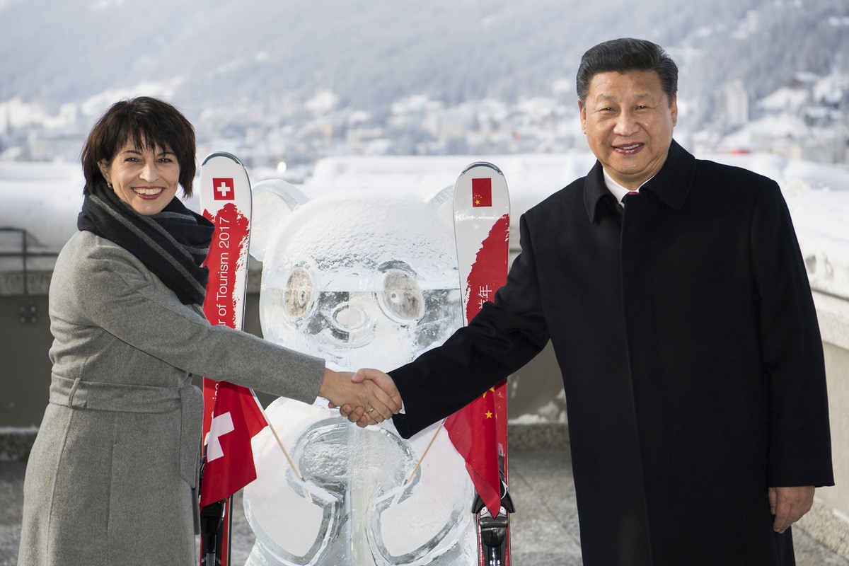Swiss Federal President Doris Leuthard, left, shakes hands with China's President Xi Jinping, right, as they launch of the Swiss-Sino year of tourism next to a panda ice sculpture on the side lin ...