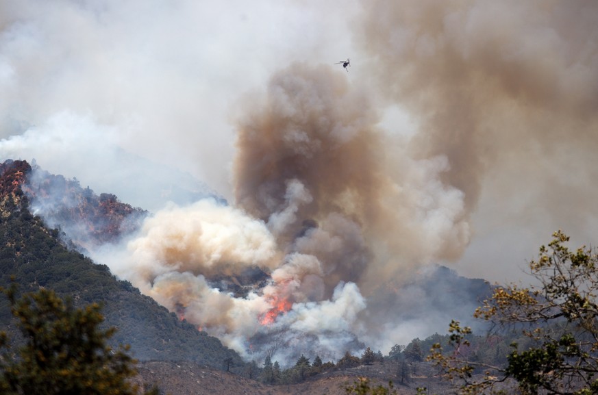 epa08581175 A firefighting aircraft drops water on the Apple Fire in Banning, California USA, 02 August 2020. The fire has burned more than 20,000 acres since it started on Friday in Riverside County. ...