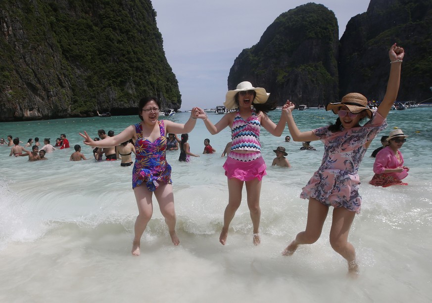 Tourists jump in the waves on Maya Bay, Phi Phi Leh island in Krabi province, Thailand, Thursday, May 31, 2018. The popular tourist destination of Maya Bay in the Andaman Sea will close to tourists fo ...