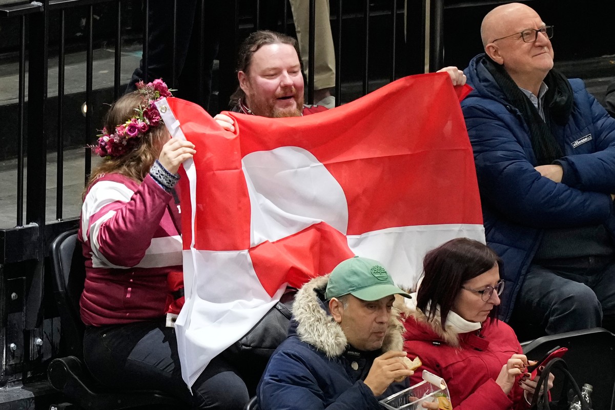 Fans hold Greenland national flag before a preliminary round match of men's ice hockey between United States and Denmark at the 2026 Winter Olympics, in Milan, Italy, Saturday, Feb. 14, 2026. (AP ...