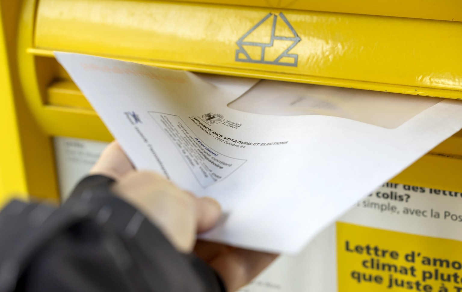Une personne effectue son vote anticipe en deposant son enveloppe concernant les votations federales et cantonales du 24 novembre dans une boite aux lettres de La Poste, ce dimanche 17 novembre 2024 a ...