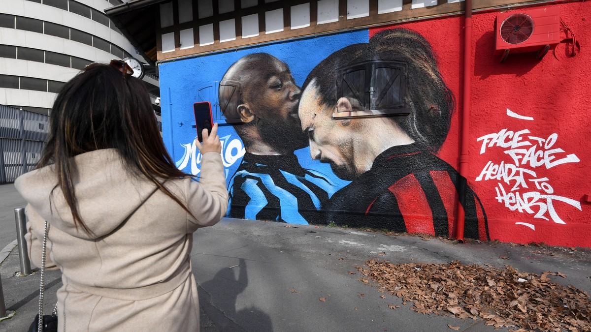 epa09014661 A woman takes a photo of a mural near the Giuseppe Meazza Stadium, depicting Inter Milan's Romelu Lukaku (L) and AC Milan's Zlatan Ibrahimovic head to head arguing during an Ital ...