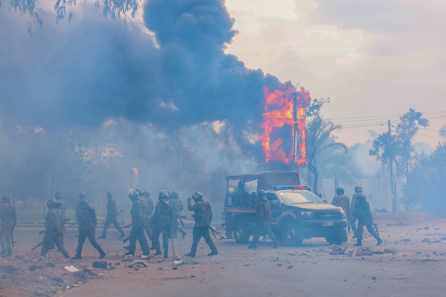 epa12197026 Anti riot police move to take up positions as the city clock post set alight by demonstrators burns during a protest in the central business district of Nairobi, Kenya, 25 June 2025. The p ...