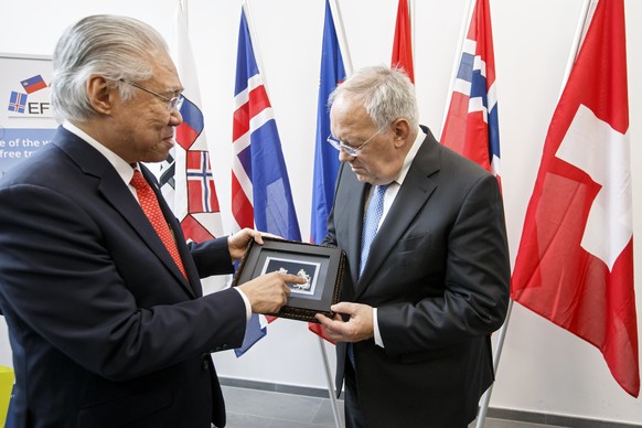 epa07184645 Indonesia&#039;s Trade Minister Enggartiasto Lukita, left, gives a present to Swiss Minister of Economic Johann Schneider-Ammann, after signing an agreement between EFTA and Indonesia, dur ...