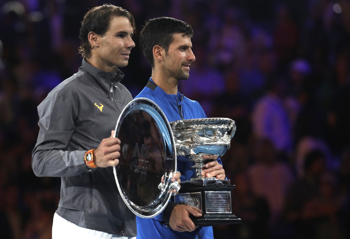 Serbia's Novak Djokovic, right, holds his trophy as he stands with Spain's Rafael Nadal after winning the men's singles final at the Australian Open tennis championships in Melbourne, A ...