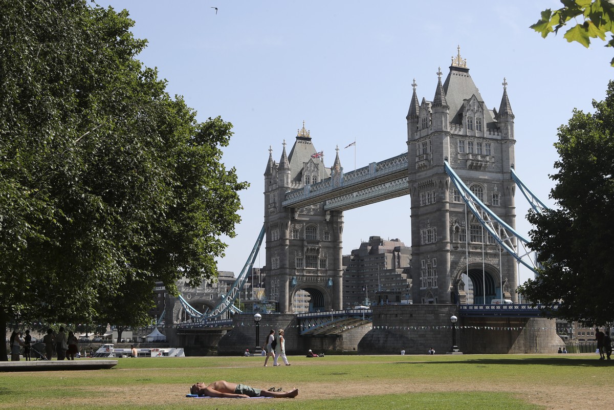 A man sunbathes backdropped by Tower Bridge in London, Tuesday July 19, 2022. Millions of people in Britain woke from the country's warmest-ever night and braced for a day when temperatures could ...