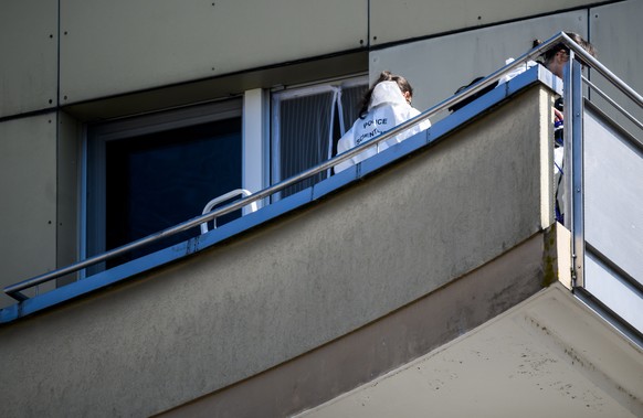 epa09846341 Two forensic police officers inspect the scene from the balcony of the building where four people were found dead and one seriously injured at the foot of a building after reportedly falli ...