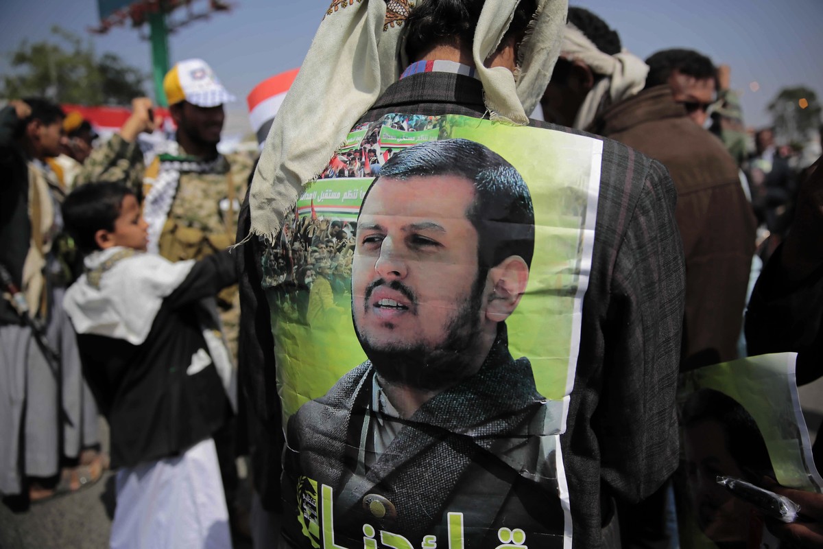 A Supporter of Houthi Shiites displays a poster of Abdel-Malek al-Houthi, the leader of Yemen's Shiite rebels, on his jacket during a rally to mark the third anniversary of the Houthis' take ...