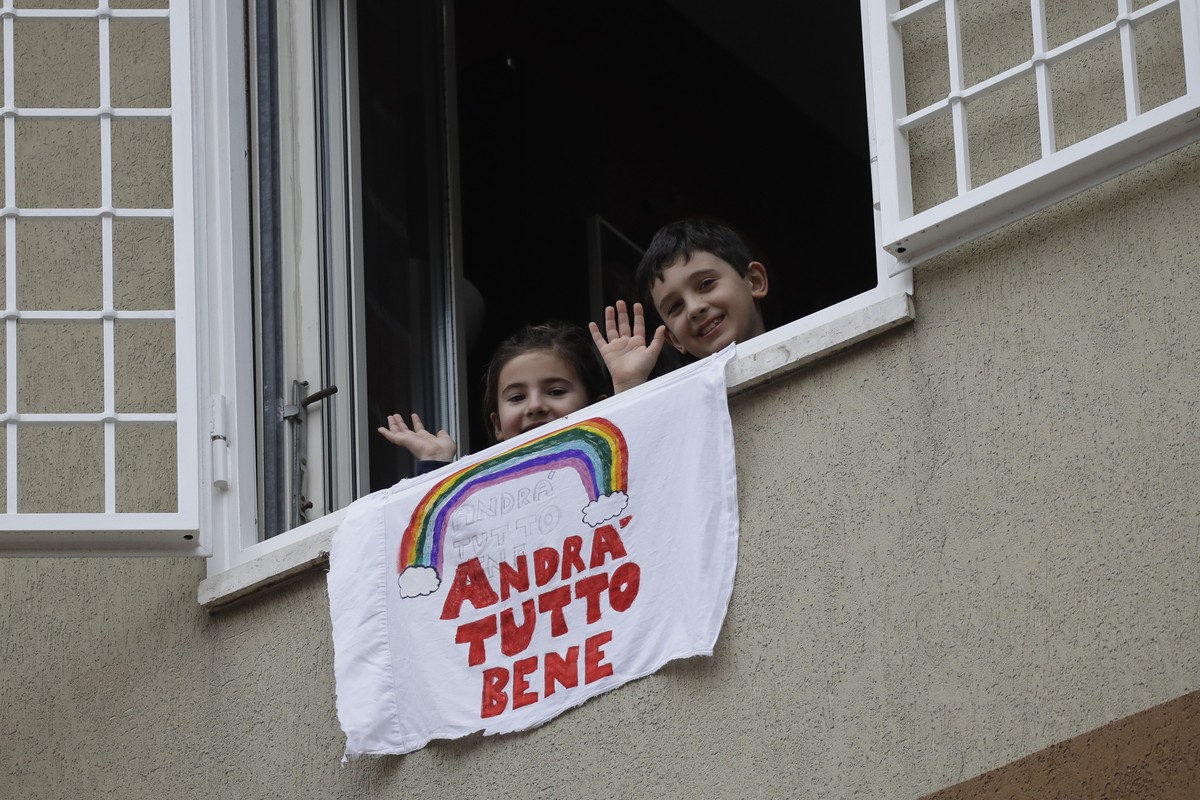 In this photo taken on Friday, March 13, 2020, Francesco and Greta Innominati wave after placing a banner reading "Everything is gone be all right" out of a window of their apartment in Rome ...