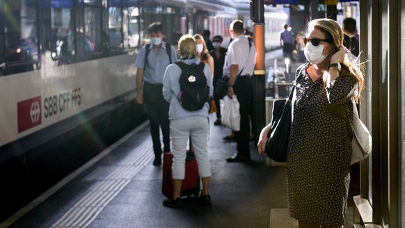 People wearing protective mask get wait a SBB CFF train during the coronavirus disease (COVID-19) outbreak, at the train station CFF in Lausanne, Switzerland, Monday, July 6, 2020. In Switzerland, fro ...