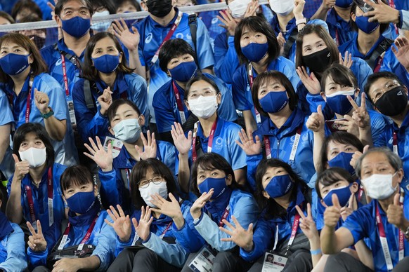 Olympic volunteers of the the Musashino Forest Sport Park, the venue for the badminton competition pose for a group photo at the 2020 Summer Olympics, Saturday, July 31, 2021, in Tokyo, Japan. (AP Pho ...