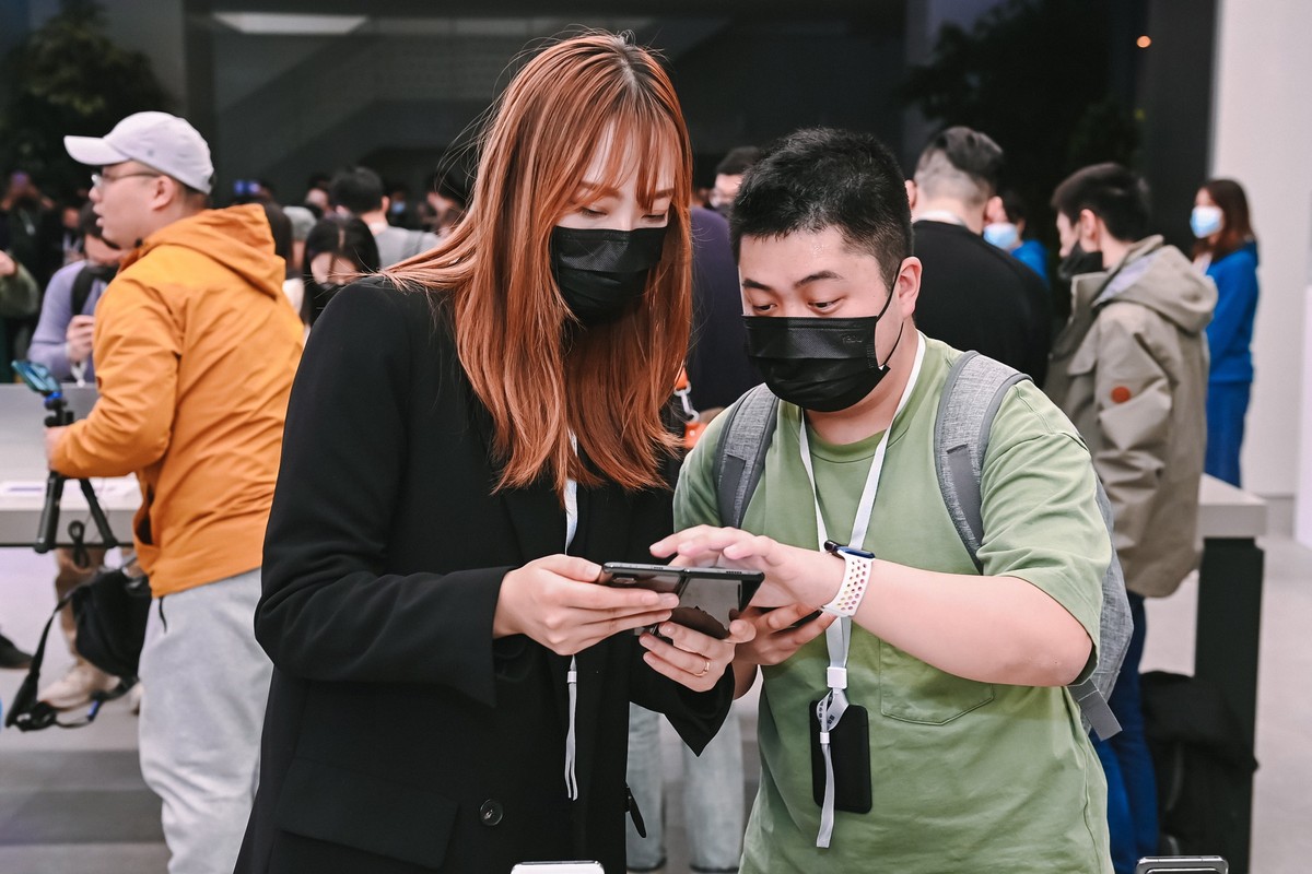 epa09107936 A handout photo made available by Xiaomi on 31 March 2021 shows people looking at Xiaomi's new foldable smartphone Mi Mix Fold during the new products unveiling event in Beijing, Chin ...