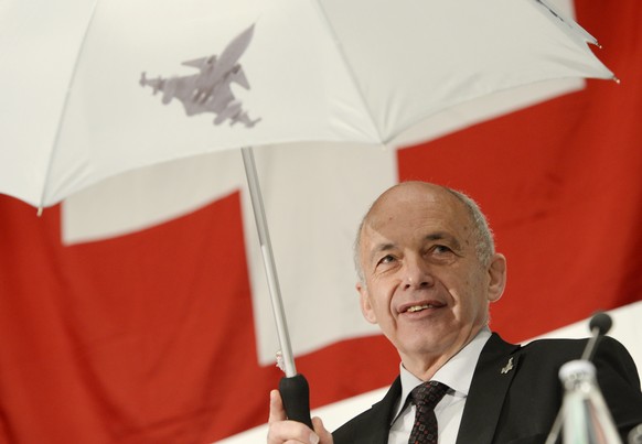 Bundesrat Ueli Maurer spannt einen Regenschirm mit dem Symbol eines Gripen Kampfjets anlaesslich der Delegiertenversammlung der SVP am Samstag, 5. April 2014, in Naefels. (KEYSTONE/Steffen Schmidt)