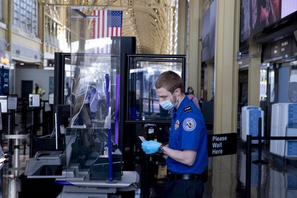 epa08839470 A Transportation Security Administration (TSA) worker checks the identification of a traveler while conducting screening at Ronald Reagan Washington National Airport in Arlington, Virginia ...