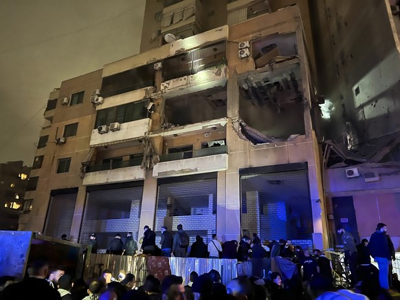 People stand outside a building after an explosion in southern Beirut, Lebanon, Tuesday, Jan. 2, 2024. (AP Photo/Hussein Malla)