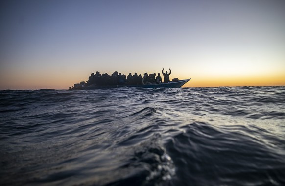 FILE - In this Feb. 12, 2021 file photo, migrants and refugees from different African nationalities wait for assistance aboard an overcrowded wooden boat, as aid workers of the Spanish NGO Open Arms a ...