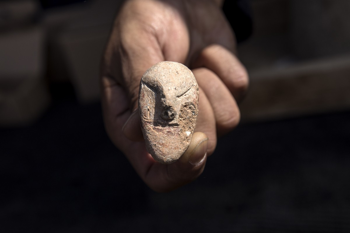 An archeologists shows a figurine found at a large, 5,000-year-old city in northern Israel. Israel's Antiquities Authority said Sunday the ancient city was discovered during preparations for a ne ...
