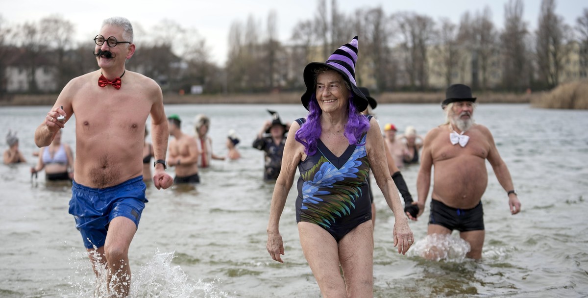 People with fancy hats and caps attend the annual New Year's swimming of the winter swimming club 'Seehunde Berlin', on New Year's Day at the Oranke Lake in Berlin, Germany, Wednes ...