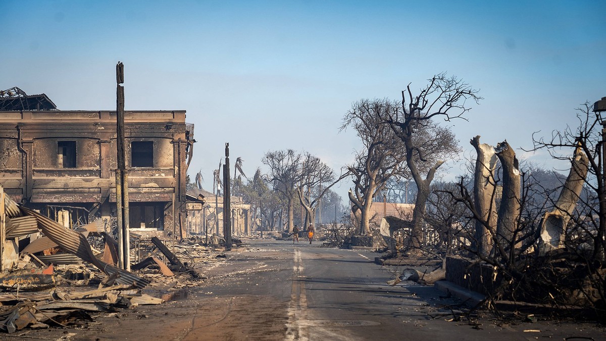 August 9, 2023, Lahaina, Maui, Hawaii, USA: Destroyed buildings and burned trees surround the area in the aftermath of the fire as residents walk down a street on Wednesday. Large sections of Lahaina  ...