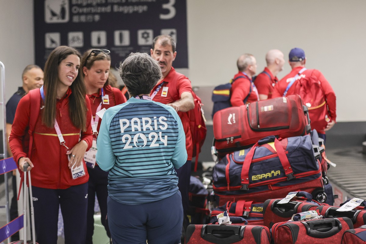 epa11493151 A Paris 2024 Olympics volunteer helps the spanish swimming Olympic delegation with their luggage at Paris Orly Airport in Orly, Paris suburbs, France, 23 July 2024. The teams at Paris-Orly ...