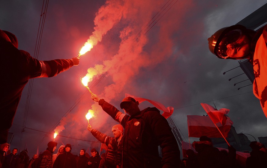 Demonstrators burn flares and wave Polish flags during the annual march to commemorate Poland&#039;s National Independence Day in Warsaw, Poland, Saturday, Nov. 11, 2017. Thousands of nationalists mar ...