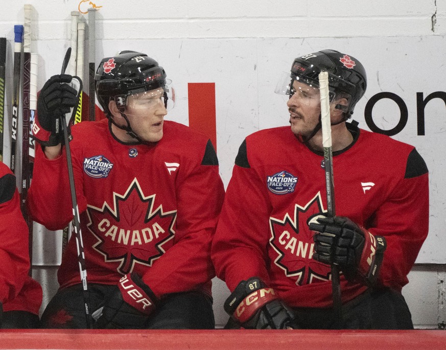 FILE - Canada players, Nathan MacKinnon and Sidney Crosby talk on the bench during 4 Nations Face-Off hockey practice in Brossard, Quebec on Feb. 10, 2025. (Christinne Muschi/The Canadian Press via AP ...