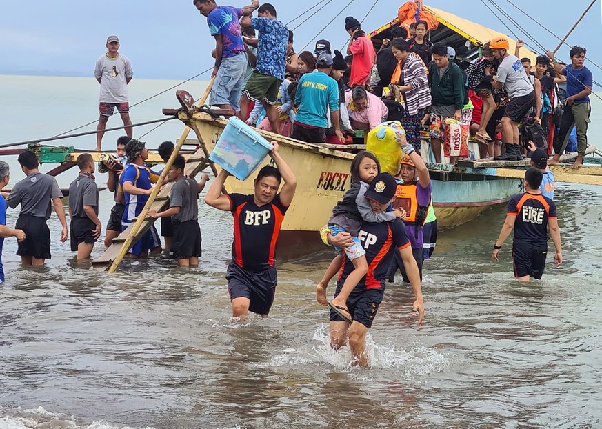 epa09887428 A handout photo made available by the Bureau of Fire Protection (BFP) - Abuyog Fire Station shows residents disembarking from a boat after their village were struck by landslide in the tow ...