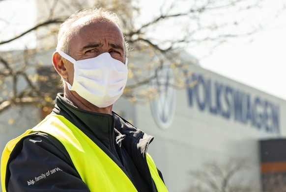 An employee wearing a face mask in front of a factory building during the production restart of the plant of the German manufacturer Volkswagen AG (VW) in Zwickau, Germany, Thursday, April 23, 2020. V ...