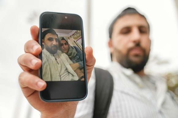 Kassem Abo Zeed holds up a photograph with his wife, Ezra, who is missing after a fishing boat carrying migrants sank off southern Greece, in the southern port city of Kalamata, Thursday, June 15, 202 ...