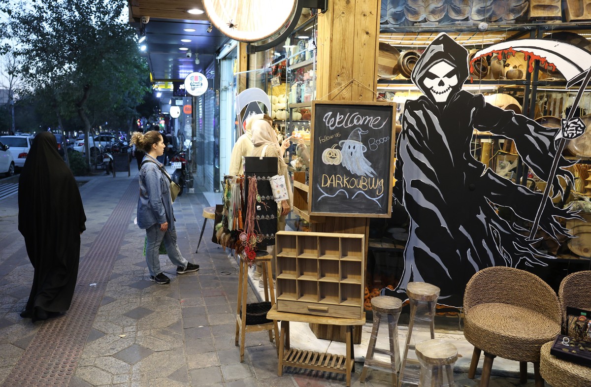 epa12490241 An Iranian woman wearing a veil walks past a shop selling Halloween decorations in Tehran, Iran, 29 October 2025. Halloween has grown in popularity among young people in Iran in recent yea ...