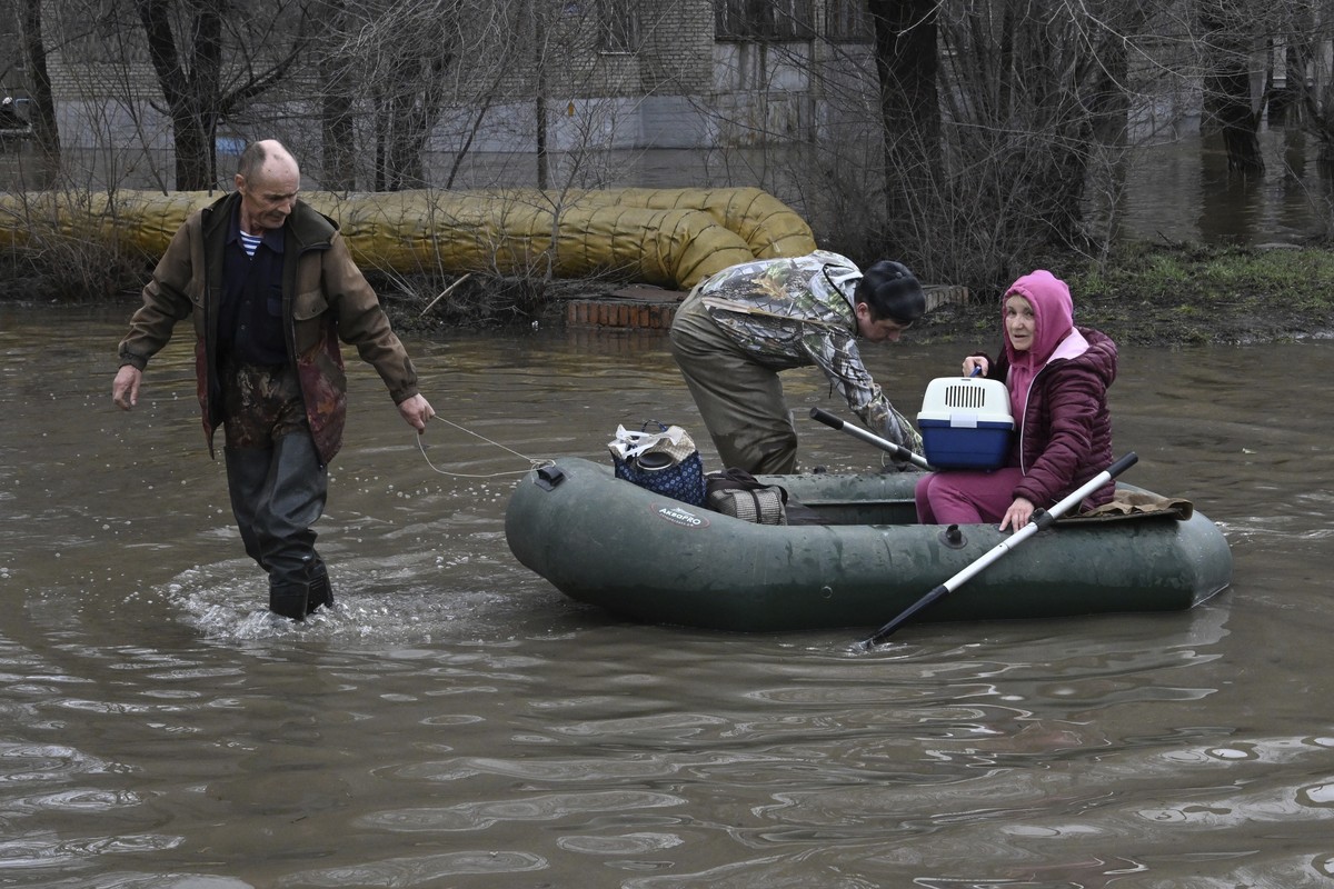 A man pulls a rubber boat carrying a woman with a cat through a flooded street after part of a dam burst, in Orsk, Russia. State media say Russia's government has declared the situation in flood- ...