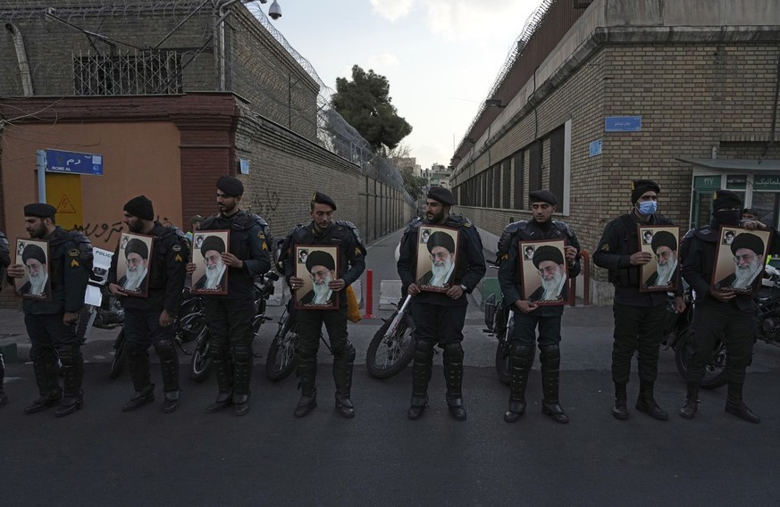Iranian police officers hold posters of the Supreme Leader Ayatollah Ali Khamenei as they protect the French Embassy during a gathering to protest against the publication of offensive caricatures of A ...