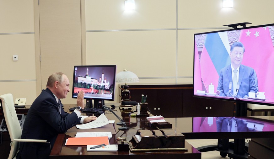 Russian President Vladimir Putin gestures during his videoconference with Chinese President Xi Jinping, right on the screen, in Moscow, Russia, Wednesday, Dec. 15, 2021. Russian President Vladimir Put ...