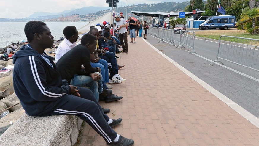 epa04803164 Migrants sit at the seaside near the French border in Ventimiglia, Italy, 16 June 2015. Hundreds of migrants have headed to Ventimiglia over the past days, as French border police started  ...