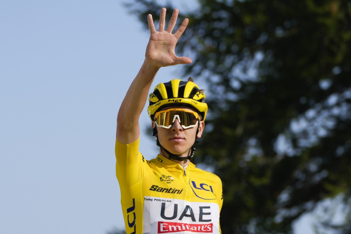 Slovenia's Tadej Pogacar, wearing the overall leader's yellow jersey, flashes five fingers for his fifth stage victory as he crosses the finish line to win the twentieth stage of the Tour de ...