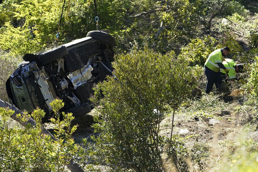 Workers remove debris near a vehicle on its side after a rollover accident involving golfer Tiger Woods Tuesday, Feb. 23, 2021, in Rancho Palos Verdes, Calif., a suburb of Los Angeles. Woods suffered  ...