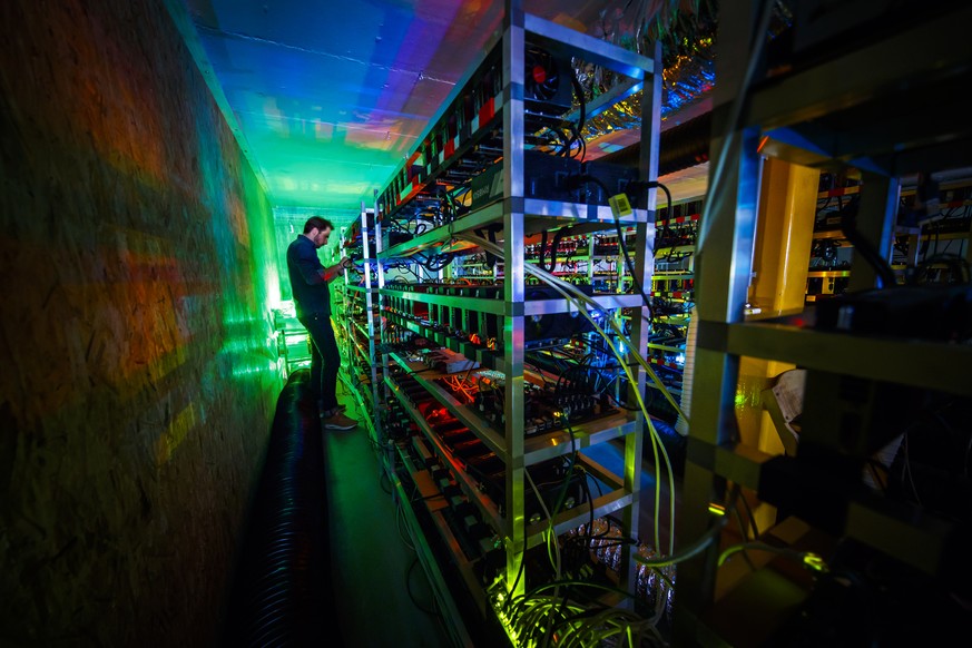 Alpine Mining employee Bertrand Deldon is lit by the LED status lights of electronic boards during a long exposure photograph at a cryptocurrency mine in the small alpine village of Gondo, Switzerland ...
