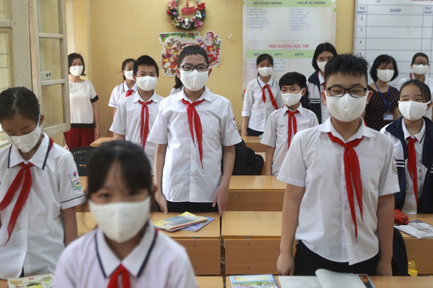 Teachers and students stand up for Vietnamese national anthem as they start a new week in Dinh Cong secondary school in Hanoi, Vietnam Monday, May 4, 2020. Students across Vietnam return to school aft ...