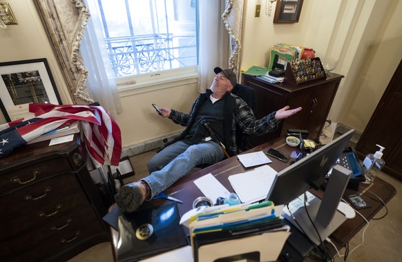 epaselect epa08923440 A supporter of US President Donald J. Trump sits on the desk of US House Speaker Nancy Pelosi after supporters of US President Donald J. Trump breached Capitol security.