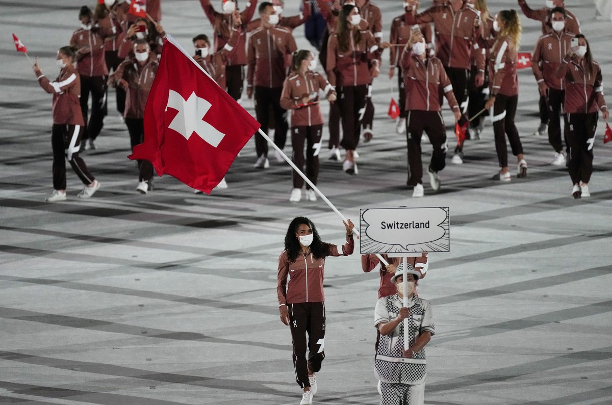 Mujinga Kambundji and Max Heinzer, of Switzerland, carry their country's flag during the opening ceremony in the Olympic Stadium at the 2020 Summer Olympics, Friday, July 23, 2021, in Tokyo, Japa ...