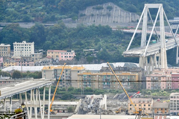 epa06970617 A general view shows the hill of Coronata of the partially collapsed Morandi highway bridge during a heavy rain alert in Genoa, northern Italy, 25 August 2018. The Morandi Bridge partially ...