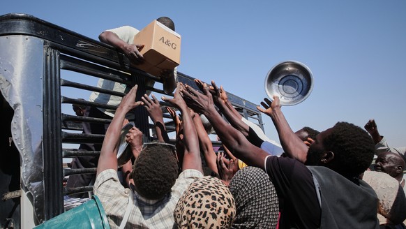 FILE - Sudanese families displaced from El-Fasher reach out as aid workers distribute food supplies at the newly established El-Afadh camp in Al Dabbah, Sudan's Northern State, Nov. 16, 2025. (AP ...