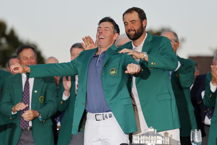 epa12030858 Last years Masters Champion Scottie Scheffler (R) helps the new Masters Champion Rory McIlroy of Northern Ireland with his Masters jacket after winning 2025 Masters Tournament at the Augus ...