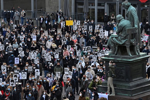 epa09023966 Participants of a demonstration commemorating the victims of a right-wing extremist shooting in February 2020 hold placards with the names and images of the victims, in front of the Brothe ...