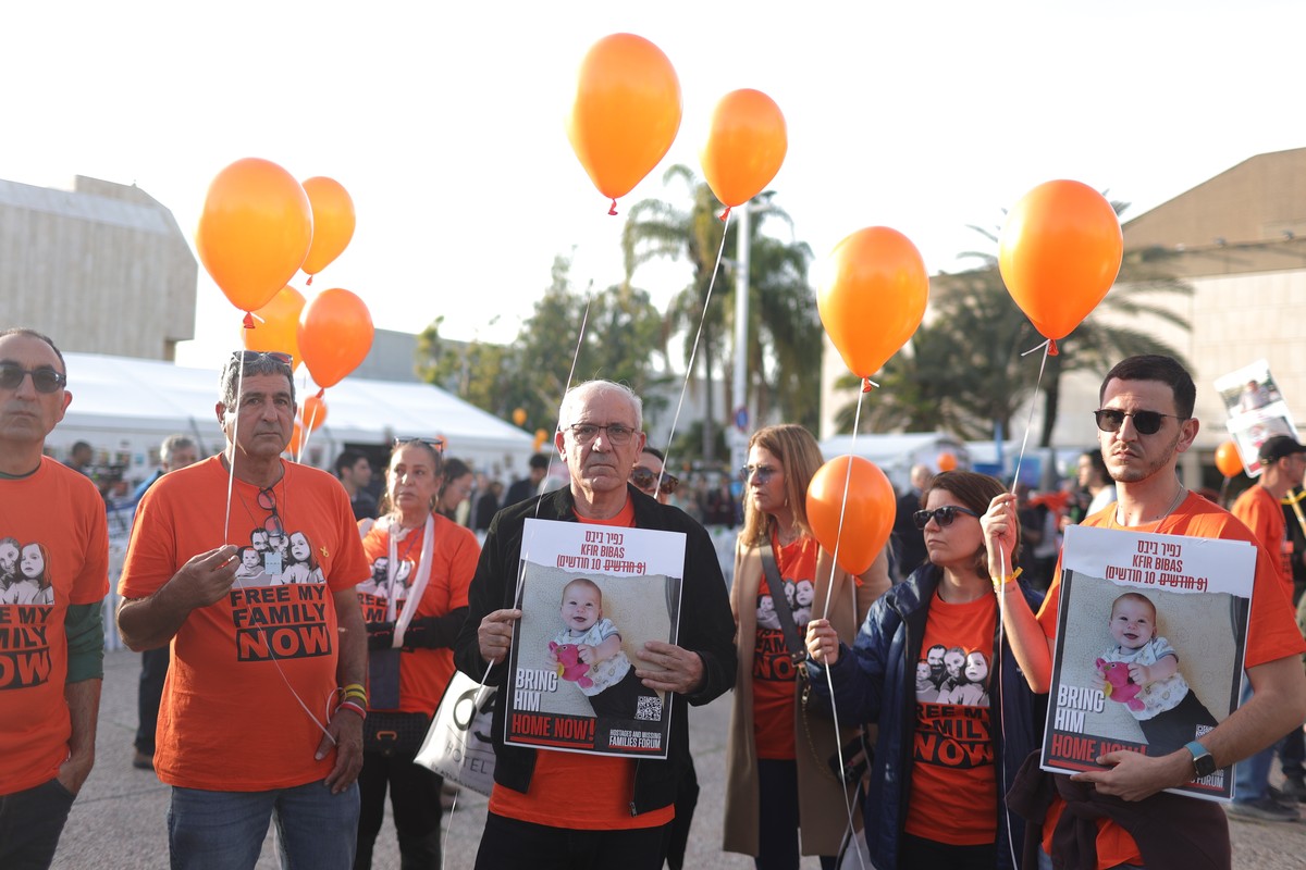 epa11087462 People hold orange balloons as they attend a ceremony to mark the first birthday of Israeli toddler Kfir Bibas, who is held hostage by Hamas in Gaza, outside the Kirya military base in Tel ...
