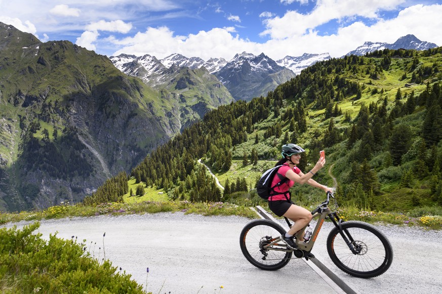 epaselect epa08522314 A person rides an E-bikes during a press tour of the discovery trail, backdroped of mountains of the Swiss Alps, on the eve of the opening of the Verbier E-bike Weekends, in Verb ...