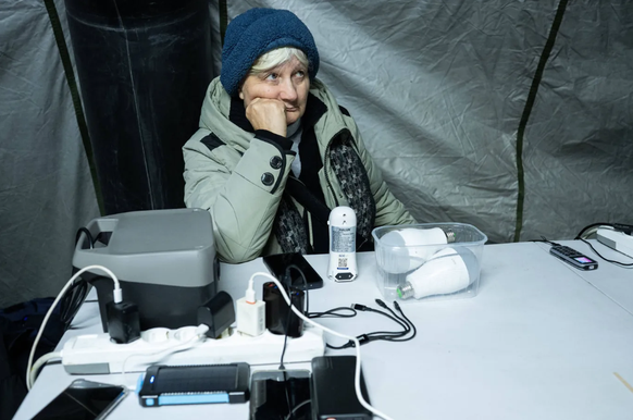 Eine Frau in einem Wärmezelt in Kiew: Dort können die Menschen auch ihre elektronischen Geräte aufladen.