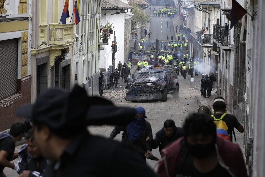 Protesters run from an oncoming armored vehicle and riot police during clashes in downtown Quito, Ecuador, Wednesday, Oct. 9, 2019. Ecuador's military has warned people who plan to participate in a na ...