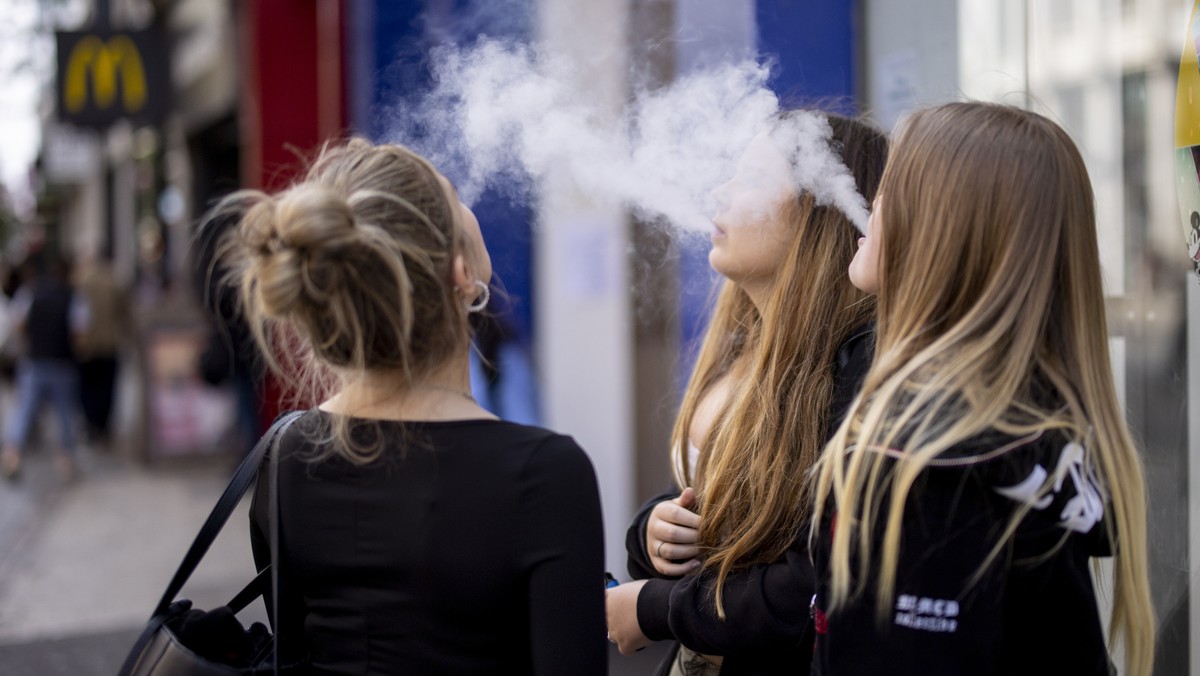 epa10663276 Young people use single-use vaping products in London, Britain, 30 May 2023. The UK government has announced it is cracking down on retailers providing free vape samples to children. The g ...