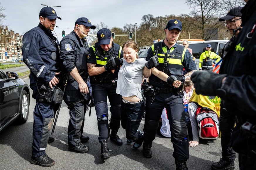 epaselect epa11262180 Swedish climate activist Greta Thunberg (C) is detained by police officers during a climate demonstration blocking the A12 highway in the Hague, the Netherlands, 06 April 2024. T ...